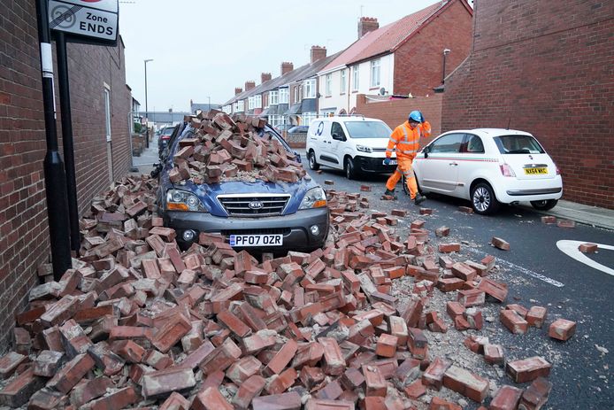A man passes by a car in the British town of Rucker, lying under fallen masonry.  The building was exposed to winds of about 160 kilometers per hour during Storm Irwin.